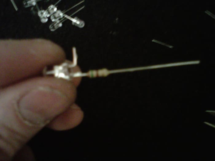 LED with - lead clipped, tinned, and bent 90-ish degrees. The + lead has the resistor soldered to it already.