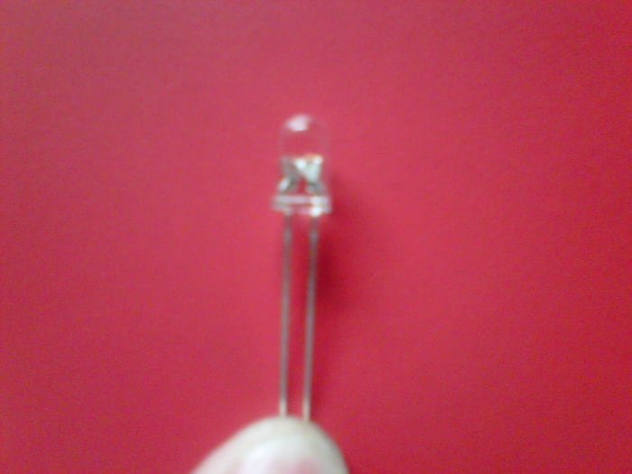 In addition to the positive leg being longer, it's also got the smaller part of the element attached inside the plastic.