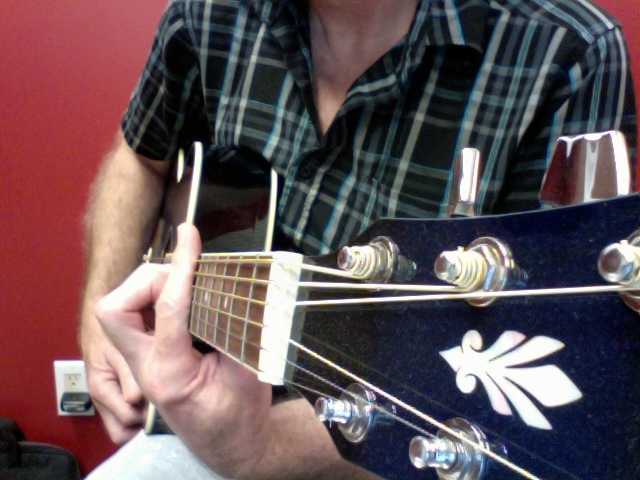 Side view of the correct hand position. Notice the index finger (the barre) is extended past the top of the fret board. This will stop your finger from bending inwards at the second knuckle and muting strings one (E) and two (B)