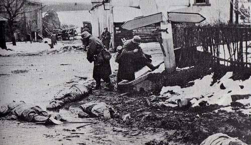 German soldiers stealing dead GI's boots in the village of Honsfeld. The road signs have been blocked out by the censors.