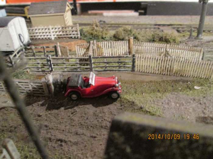 A snazzy looking sports car stands beside the livestock dock. View looking over the smithy roof