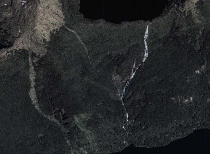 Browne Falls is located on a steep cliff coming down from a lake above. The falls can be seen in the picture as the white streak coming down from Browne Lake at the top of the picture.
