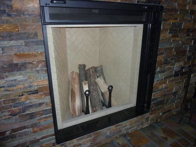 Wood leaning tepee style, within a pair of andirons, placed within a Rumford herringbone firebox, lining a metal prefab, installed in a brick wall.