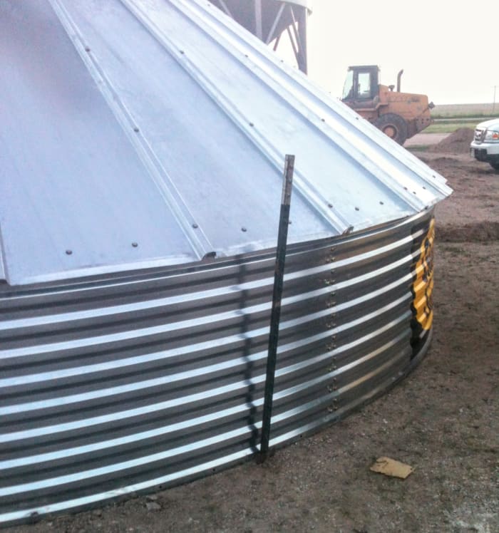 This T-post has been driven in at a slight angle to wedge against the base of the sheets. Others are spaced out around the bin. The ground was excessively hard. We refrained from wiring the posts to the roof sheets.