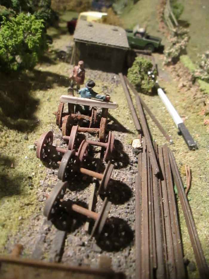 Assorted lineside detritus, plastic axles and wheels painted to resemble rusted steel. At the back is a pair of Ratio sheds fixed together, painted and weathered to look like creosoted timber