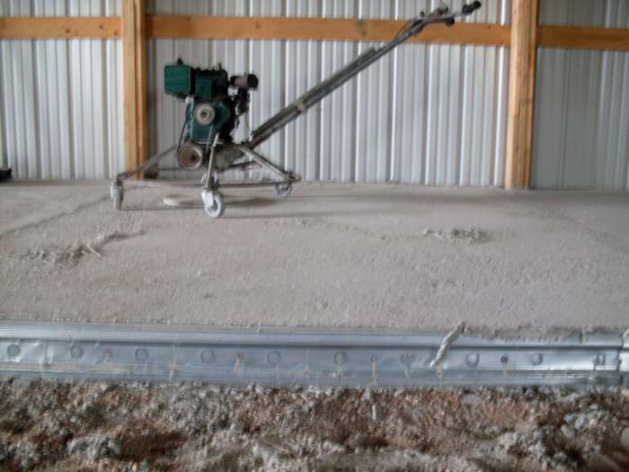 A machine to smooth the leveled underlayment for the concrete pad sits off to the side, on a section which has already been done.