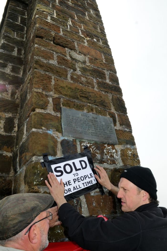 Craig Hornby attaches the 'sold' notice, to show FOEH have bought the parcel of land around the Nab