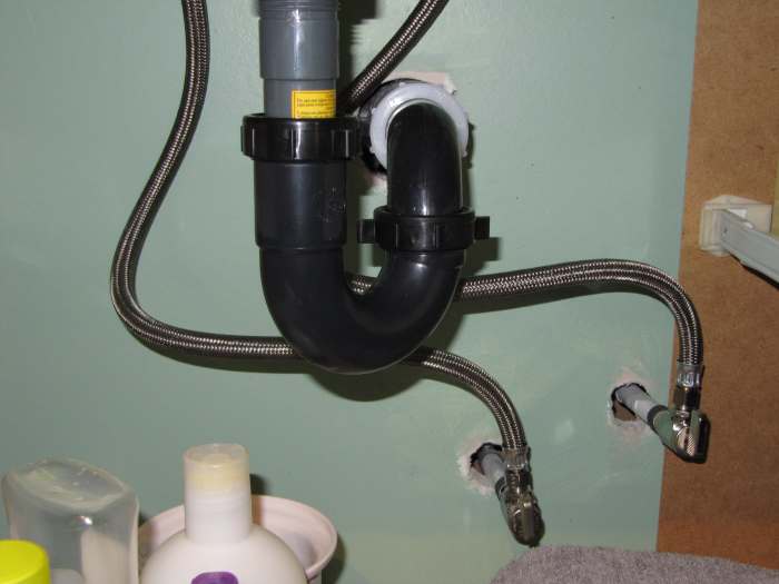 This picture is of under a bathroom sink showing the shut off valves and the flexible water supply lines going up to the taps.