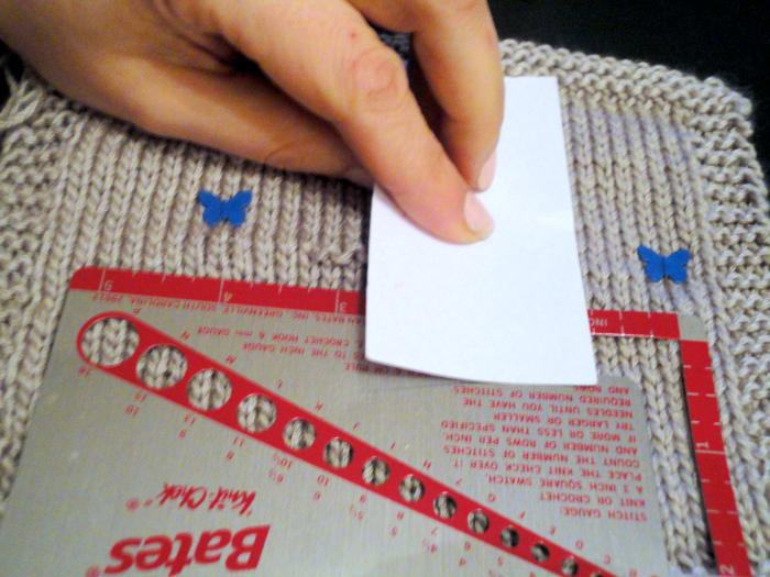 Using a knit-check ruler by Susan Bates, sewing pins and a business card, carefully count your stitches and rows.