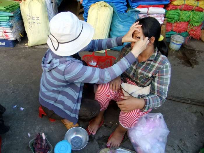 My travel to Vietnam: This woman was helping to trim her friend's eyebrow, while waiting for people to buy the plastic products at Dong Ba market in Hue. Looking pretty is still important in any part of the world.