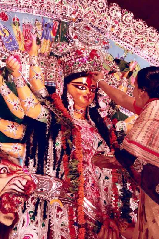 Sindur or vermillion being applied to Goodess Duga on Dashmi day