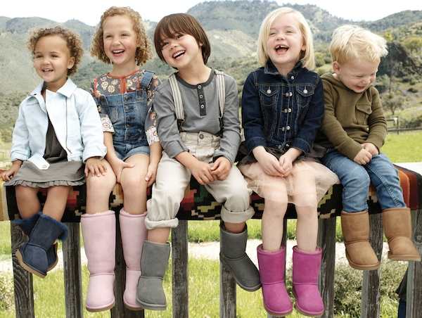five children sitting and laughing on a bench with mountains behind them all wearing Uggs boots in different colors
