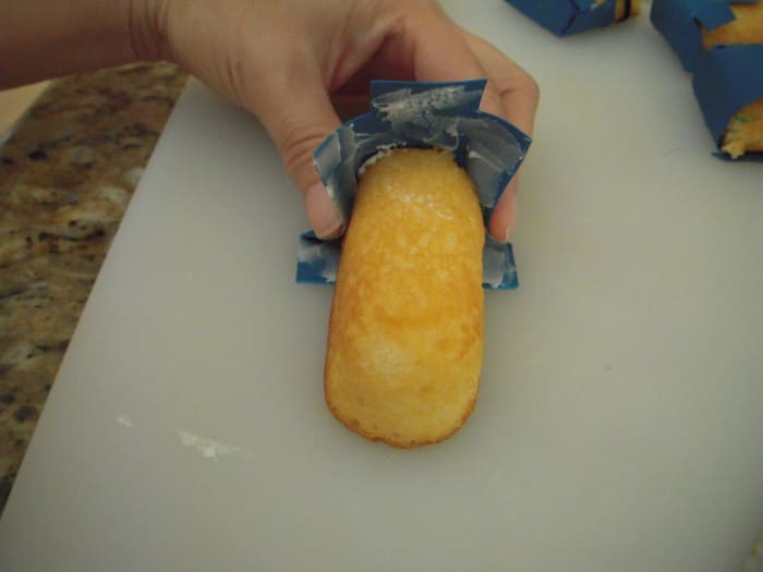 Gently press the bottom and sides of the overalls around the Twinkie. Then press the front and back of the overalls against the Twinkie. (Kind of like putting on a diaper.)