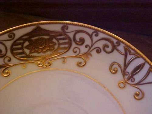 Christmas Ball has a white ground with a yellow border and heavy applied gold enameling in a scrolling pattern with flowers in a ball or bulb form.