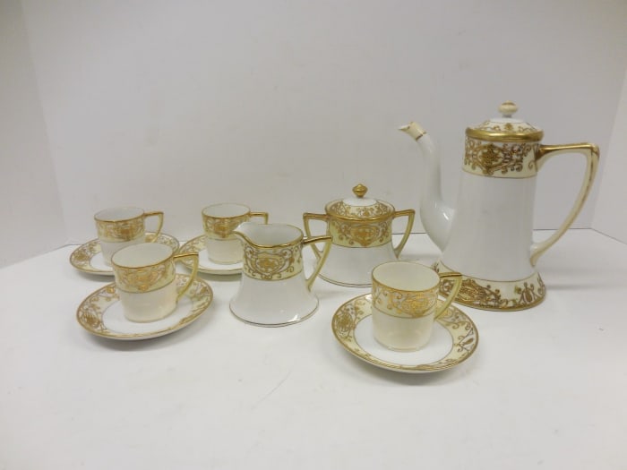 NORITAKE CHRISTMAS BALL 13 PIECE DEMITASSE SET. The coffee pot stands 6.5" high and 6.5" wide with some gold loss on the handle. The creamer is 2.5" high and 3" wide. The sugar bowl is 3.5" high and 4" wide. The saucers are 4" in diameter and the