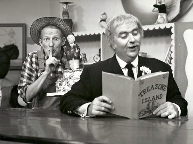 Captain Kangaroo reading from "Treasure Island" while Mr. Green Jeans looks on
