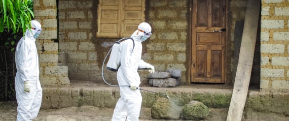 A healthcare worker in protective gear sprays disinfectant around the house of a person suspected to have Ebola virus in Port Loko Community, situated on the outskirts of Freetown, Sierra Leone, Tuesday, Oct. 21, 2014