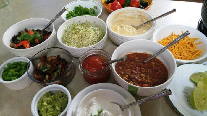 Examples of some of the toppings for a 'vegan' Baked Potato Bar: 2 kinds of bean dishes, cilantro, green onion, tofutti sour cream, salsa, hummus, guacamole, garlic mushrooms, sauerkraut, kimchee, vegan cheese shreds, alfalfa sprouts.