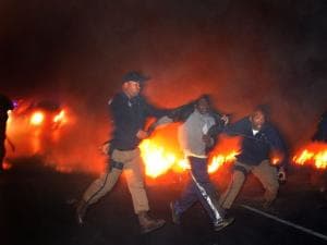 A protester is arrested by metro police officers after a group of about 40 people burned tires and barricaded a section of the N2 early this morning, July 14th 2011