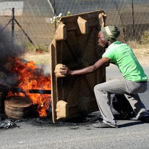 A protester shields himself from rubber bullets fired by the police during in Zandspruit settlement in northwest Johannesburg violent service delivery protest