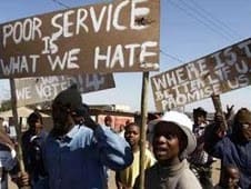 Protesters holding up signs that voice their displeasure which is routinely ignored by the ANC-led government