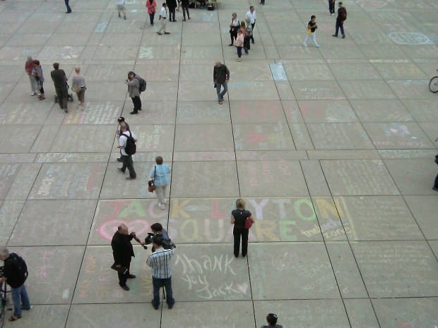 Messages in honour of Jack Layton written in chalk cover the pavement of Nathan Phillips Square in Toronto.