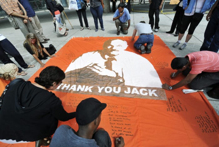 People pay their respects as they write messages on the sidewalks and a banner remembering late NDP leader Jack Layton in Toronto City Hall in Toronto on Friday, Aug. 26, 2011.