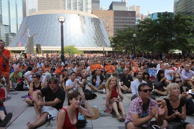 Crowds of people filled David Pecaut Square in downtown Toronto to watch the service on large television screens. Roy Thomson Hall, where Laytons funeral was held, is seen in the background.