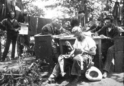 In a posed photograph, while one soldier mends his clothing, others behind him make use of confiscated pews and write letters home. The men in the background pose by laundry or with a newspaper