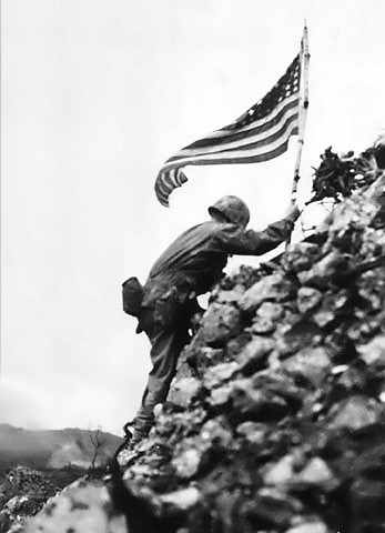 Lt. Col. Richard P. Ross commander of the 1st Battalion, 1st Marines braves sniper fire to place the divisions colors on a parapet of Shuri Castle on the 30th of May 1945. The flag was first raised over Cape Gloucester and then Peleliu.