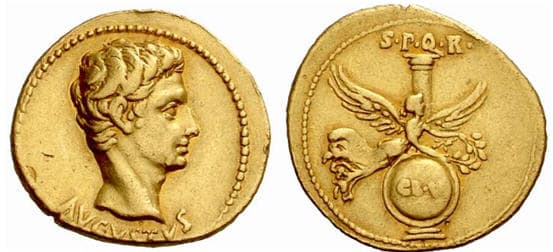 Bare head of Emperor Augustus on the left and Victory with her wings spread on the right, at the back is a column and a shield below.