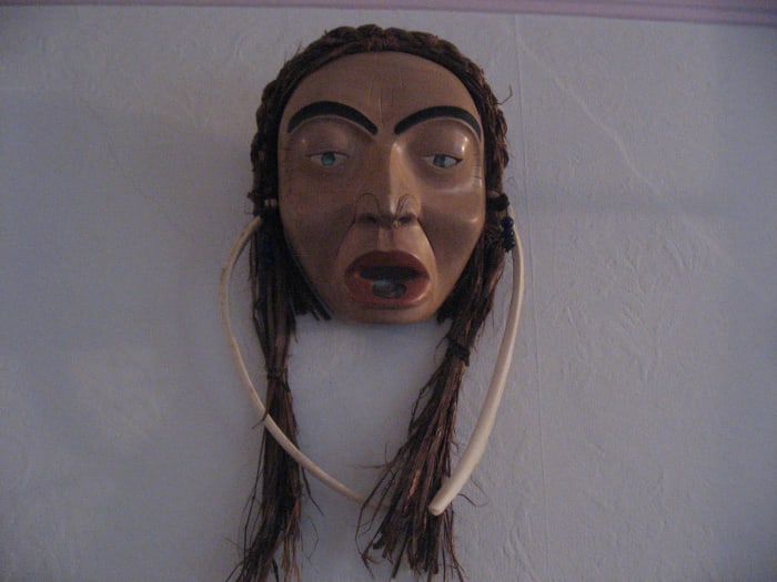 Older woman with labret and bone earrings.This is carved in North West Coast style from Alder with cedar bark hair. it was carved by Marsha Ablowitz