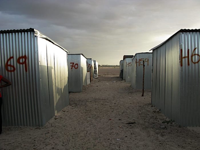 The lining up of and making of the tin shacks row of corrugated structures which were mostly one room(so to speak) and were finally enclosed in barbed wire forming the Blikkiesdorp Tin Shack Town