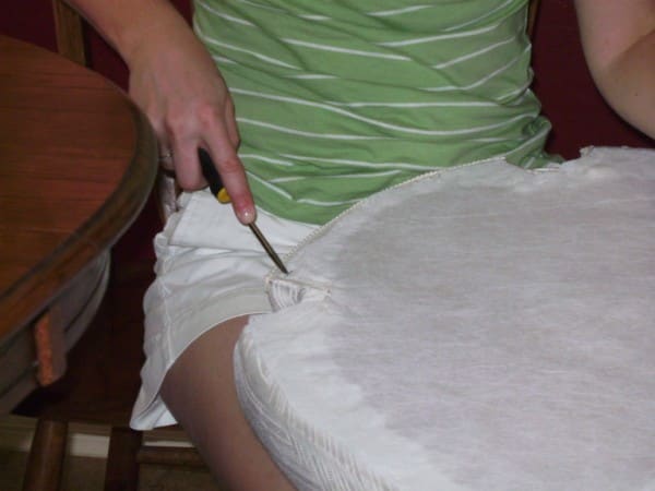 If you remove the existing fabric, use a flat head screw driver to pry the staples out of the wood seat bottom. You may need to pull the staples out with pliers after you loosen them with the screwdriver.