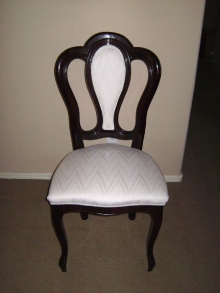 The chair originally had a dark cherry colored shiny finish with white upholstery on the seat and the back