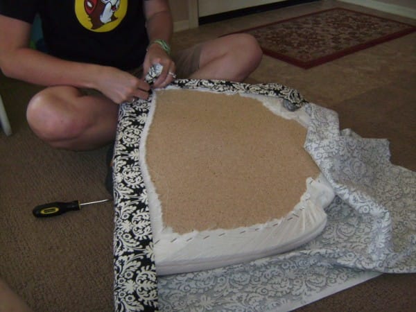 Once the fabric is stapled to the front and back of the cushion, work your way around the sides of the cushion, stapling as you go.