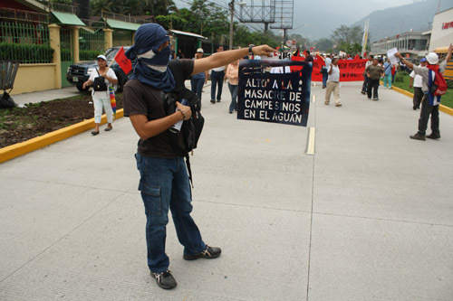 During a march of February 2010 in San Pedro Sula, a youth who was pro-democracy holds a sign which read: "Stop the massacre of the peasants in Aguan