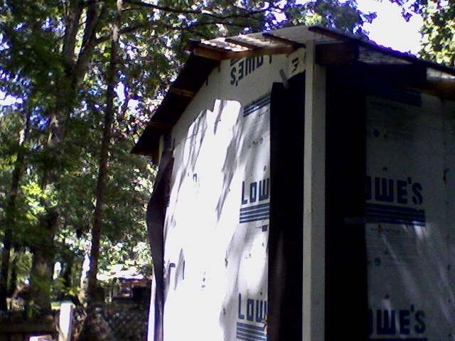 Corners with trim installed over the tar paper. The duct tape has come unstuck on the far corner, causing a sag.