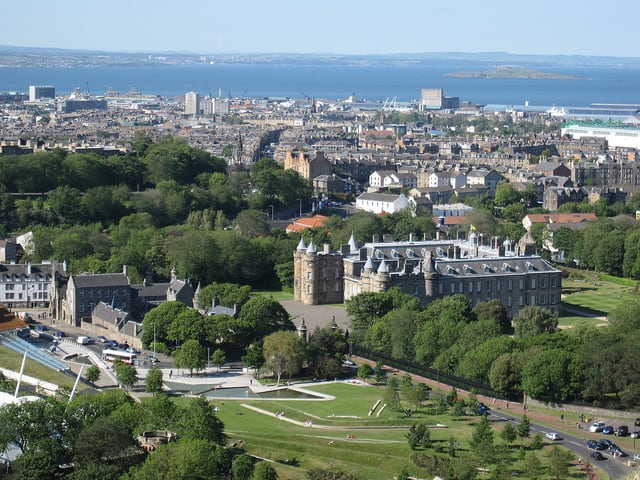 Holyrood Palace, Edinburgh, the official royal residence in Scotland, with the blue waters of the Firth of Forth shining int he distance.