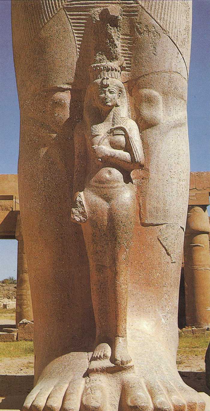The dimunitive figure of a graceful queen Nefertari standing between the legs of the colossal granite state of Ramesses II in the first courtyard of the temple at Karnak; maybe his daughter Bint-Anath, whose mother was Istnofret