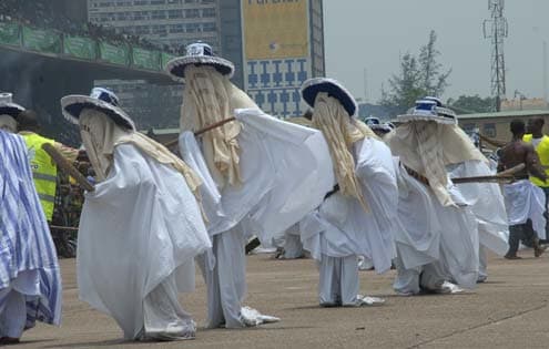 A typical procession of the Eyo masquerades dancing and moving along through the streets of Lagos Island.