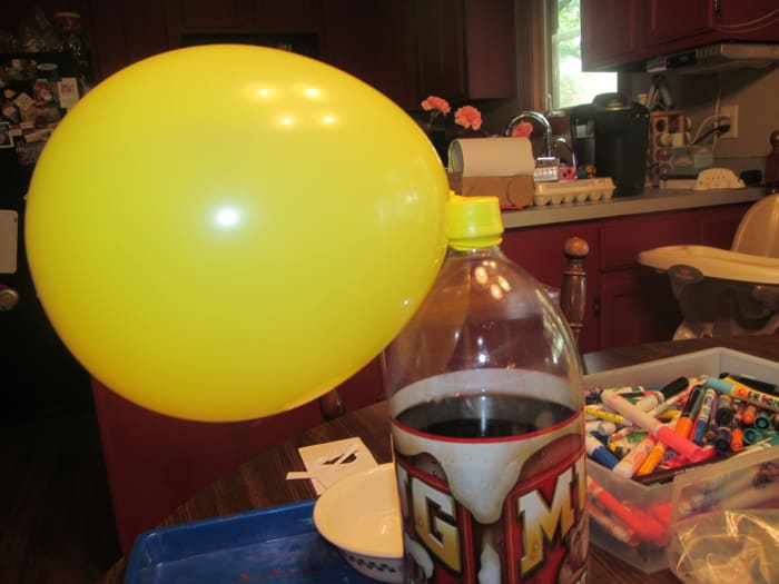 Carefully attach the end of the balloon to the top of a 2 liter bottle, it works better if the bottle is full of something so it is heavy and doesn't move.