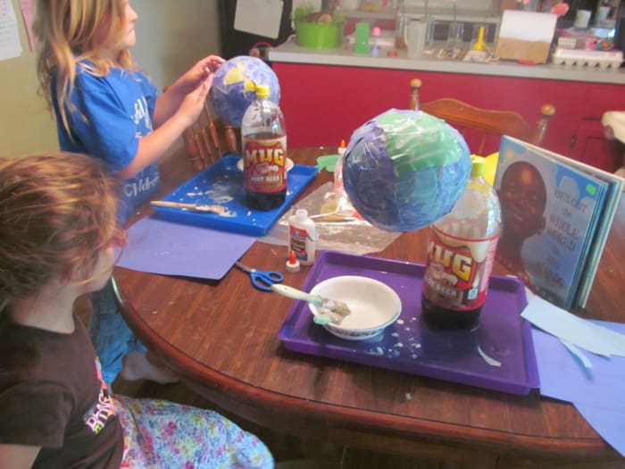 Continue adding pieces until the whole balloon is covered with glue. We usually do one more coat of paste to smooth it out. Then lay your green in place and paste in on top of the blue.