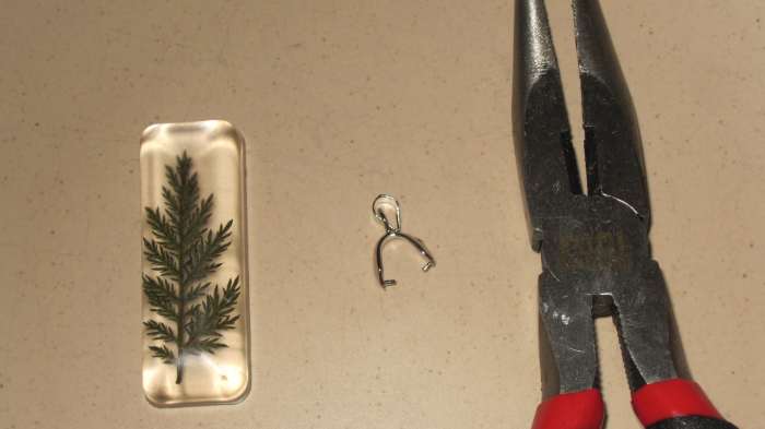 Gently spread the pinch bail open with pliers so it will fit over the top the of the pendant.