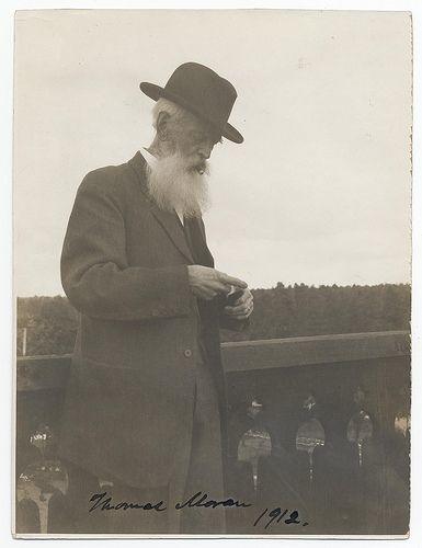 Moran standing on a balcony, smoking a cigar. Inscription lower left: "Thomas Moran, 1912". Moran, Thomas, 1837-1926