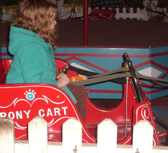 A young girl enjoys the Pony Carts, one of several vintage amusement park rides at Crossroads Village.