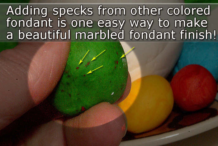 Create marbled fondant by adding specks of other colors or unincorporated food colors, then knead the fondant and roll out as usual.