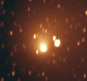 This photo shows an object following the comet with a black exhaust trail behind it and stars in the background.