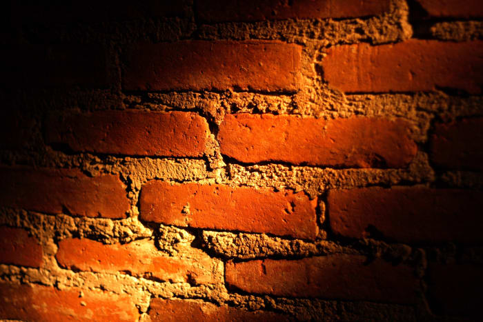 A brick wall partially illuminated by a ray of light. The light that separates the light from the dark.