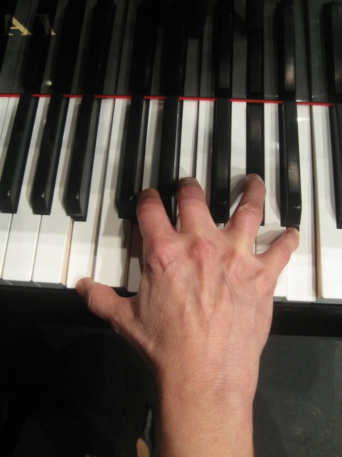The same woman's hand playing a seventh chord on the slightly smaller 15/16th piano..